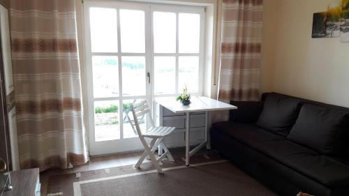 a living room with a couch and a table and a window at Appartement-Harlachberg-Blick-2 in Bodenmais