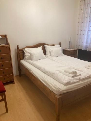 a bed with a wooden headboard and white sheets at Cédrus apartman in Pécel