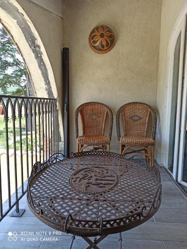 - une table en fer forgé et 2 chaises sur une terrasse couverte dans l'établissement La Bohême, à Charols
