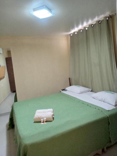 a bedroom with two beds with green sheets and a towel at Pousada Familly -Praia de Tambaú -PB in João Pessoa