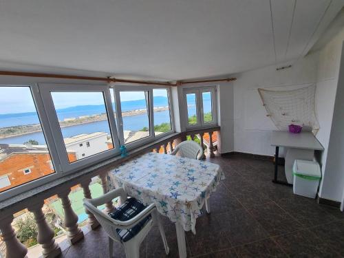 a room with a table and a balcony with windows at Apartman Nika in Omišalj