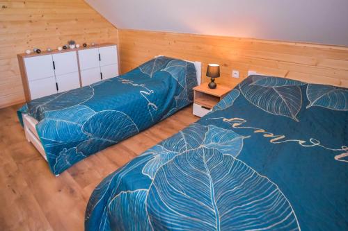 a bedroom with two beds with blue sheets with leaves at ZACISZE W OGRÓDKU Dom z balią i sauną in Ogródek