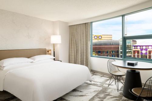 a hotel room with a bed and a large window at Sheraton Cerritos in Buena Park