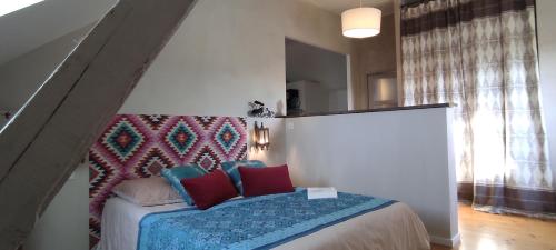 sypialnia z łóżkiem z czerwonymi i niebieskimi poduszkami w obiekcie La Lagosienne 