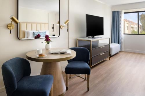 a hotel room with a table and chairs and a tv at The Anza-a Calabasas Hotel in Calabasas