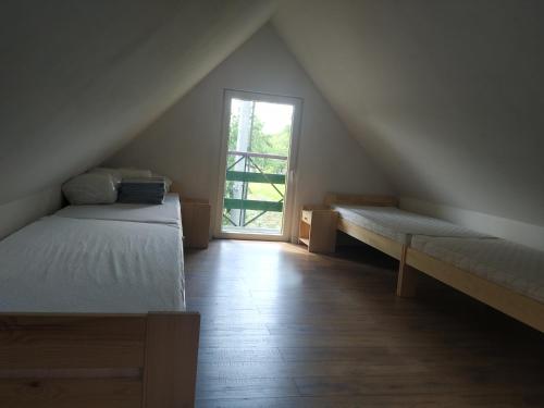 um quarto no sótão com 2 camas e uma janela em Domek w Bieńkówce 