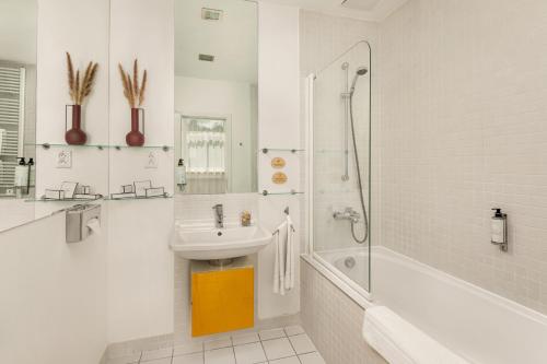 a white bathroom with a sink and a shower at Mamaison Residence Sulekova Bratislava in Bratislava