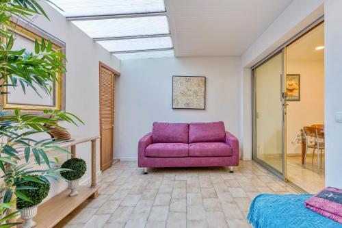 - un canapé violet dans une chambre avec une table dans l'établissement Appartement Hubble - Welkeys, à Cagnes-sur-Mer