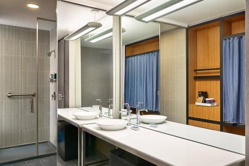 een badkamer met 3 wastafels en een spiegel bij Aloft Denver Airport at Gateway Park in Aurora