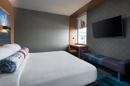 ein Hotelzimmer mit einem Bett und einem Flachbild-TV in der Unterkunft Aloft Denver Airport at Gateway Park in Aurora