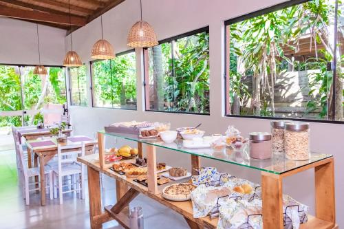 a breakfast table with food on it in a room with windows at Pousada Morro das Palmeiras in Praia do Rosa