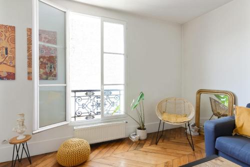 - un salon avec un canapé bleu et 2 fenêtres dans l'établissement Appartement Luciole - Welkeys, à Paris