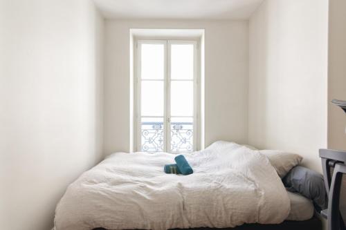 un lit dans une chambre avec une fenêtre dans l'établissement Appartement Luciole - Welkeys, à Paris