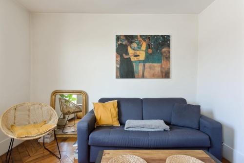 - un canapé bleu dans le salon orné d'une peinture murale dans l'établissement Appartement Luciole - Welkeys, à Paris