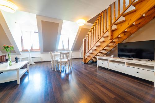 a living room with a large television and a staircase at Apartamenty Portowe in Mikołajki