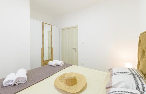 a straw hat sitting on a bed with towels at Djukic Apartmani in Tivat