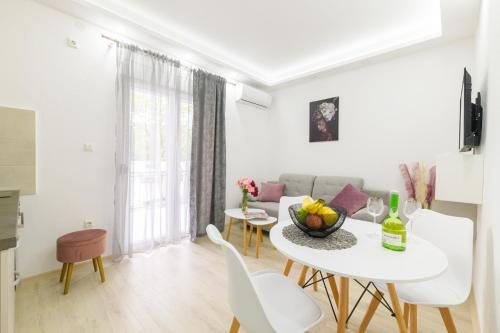 a white living room with a white table and chairs at Djukic Apartmani in Tivat