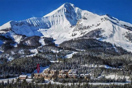 uma montanha coberta de neve com um alojamento de turismo selvagem em frente em Lone Mountain Retreat em Big Sky