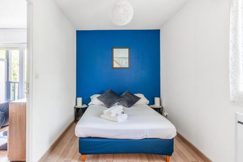 un lit dans une chambre avec un mur bleu dans l'établissement Appartement Aurora - Welkeys, à Houlgate