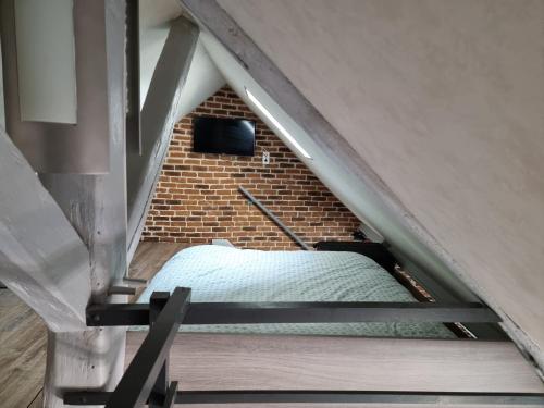 an attic bedroom with a bed in a brick wall at Appartement atypique climatisé in Semur-en-Auxois