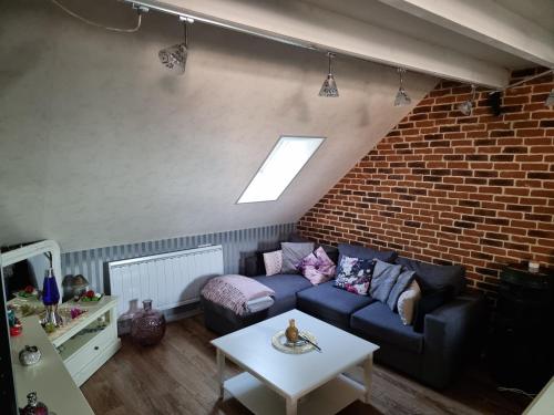 a living room with a blue couch and a brick wall at Appartement atypique climatisé in Semur-en-Auxois