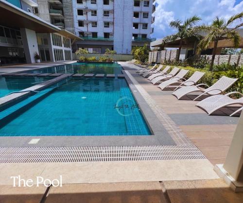 a swimming pool with lounge chairs and a building at Lovely Studio Condominiums at Mesavirre Garden Residences Bacolod in Bacolod
