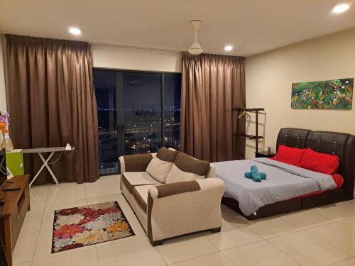 a bedroom with a bed and a couch and a chair at TREFOIL@SETIA CITY, STUDIO UNIT,HOMESTAY in Shah Alam
