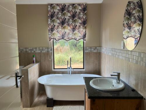 a bathroom with a tub and a sink and a window at Thabazimbi Country Lodge in Thabazimbi