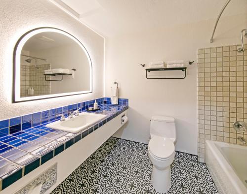 een badkamer met een wastafel, een toilet en een spiegel bij Half Moon Bay Lodge in Half Moon Bay