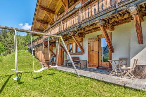 une maison en bois avec une terrasse couverte et une balançoire dans l'établissement Le Chalet du Berger - Welkeys, à Praz-sur-Arly