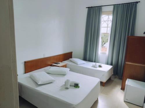 a hotel room with two beds and a window at Grande Hotel Bragança in Bragança Paulista