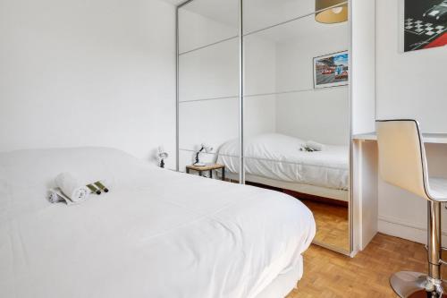 une chambre avec un lit blanc et un miroir dans l'établissement Appartement Garibaldi - Welkeys, à Paris