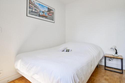 - un lit blanc dans une chambre avec une photo sur le mur dans l'établissement Appartement Garibaldi - Welkeys, à Paris