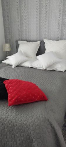 a red pillow sitting on a bed with white pillows at LUXURY AQUA APARTMENTS przy AQUAPARK REDA in Rumia