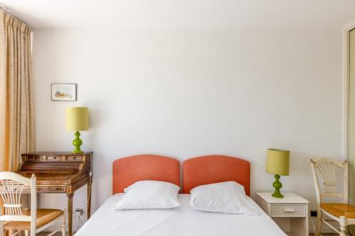 - une chambre avec un lit avec une tête de lit orange et un bureau dans l'établissement Appartement Orangerie - Welkeys, à Antibes