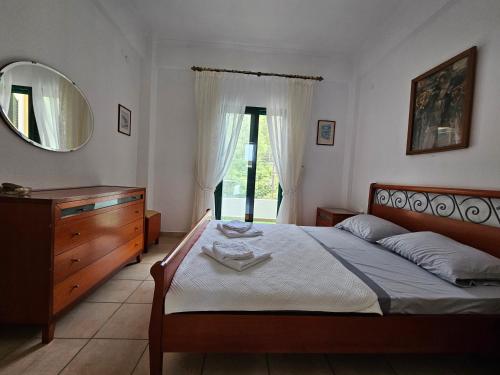 a bedroom with a bed and a dresser and a mirror at Cosy apartment by the sea in Nea Potidaea