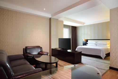 a hotel room with a bed and a couch and chair at Four Points by Sheraton Medan in Medan
