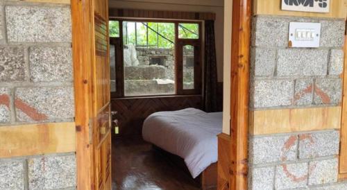 a small bedroom with a bed and a window at Hostelam in Manāli