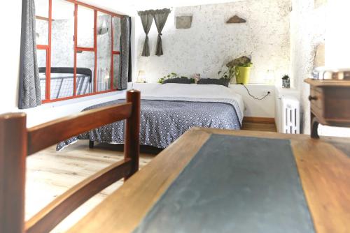 a bedroom with a bed and a table in a room at Le Gîte des Cimes in Tulle