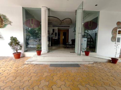 an entrance to a white building with potted plants at The Sky Imperial Hotel Yahvi in Vadodara