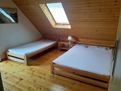 a attic room with two beds and a window at Domki Nad Strumykiem in Krościenko