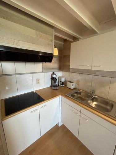 a small kitchen with white cabinets and a sink at Hotel Halleux in Banneux