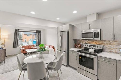 uma cozinha e sala de estar com mesa e cadeiras em Quiet, modern, stylish, one King & two Queen size beds, central location, parking em Winnipeg