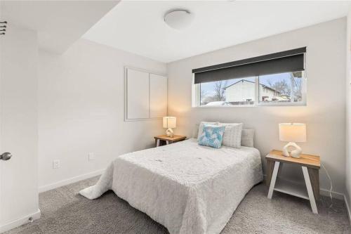 1 dormitorio con 1 cama con ventana y 2 lámparas en Quiet, modern, stylish, one King & two Queen size beds, central location, parking en Winnipeg