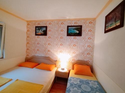 ウトイェハにあるApartmani LJUBICAのベッド2台、壁に照明が備わる小さな客室です。