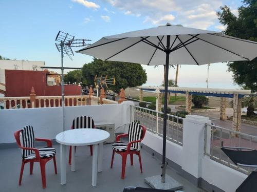 a patio with a table and chairs and an umbrella at BeachFront House in Málaga