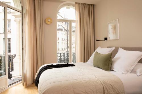 ein Schlafzimmer mit einem Bett und einem großen Fenster in der Unterkunft Résidence Nell Paris in Paris