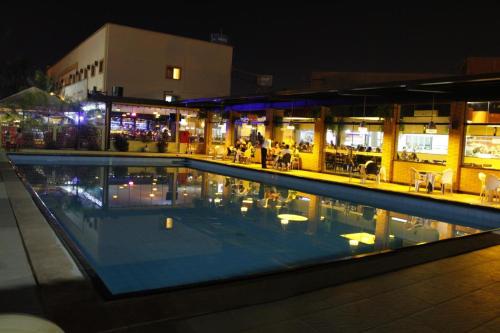 a swimming pool at night with a restaurant in the background at HOTEL ITACAIUNAS in Marabá