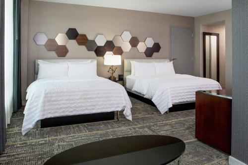 um quarto de hotel com duas camas com lençóis brancos em Le Meridien Boston Cambridge em Cambridge