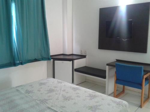 a bedroom with a bed and a desk and a tv at HOTEL ITACAIUNAS in Marabá